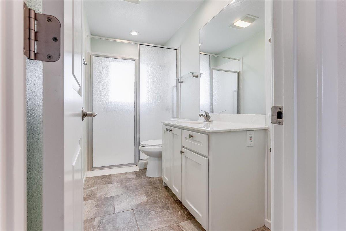 2801 62nd Street Lubbock, TX 79413 - Photo 19 of 21 a bathroom with a granite countertop sink a toilet a shower and a mirror