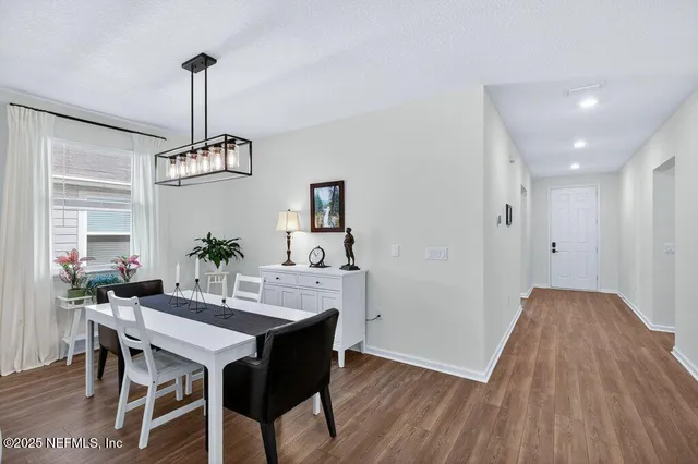 a kitchen with stainless steel appliances granite countertop a stove a sink dishwasher a dining table and chairs with wooden floor