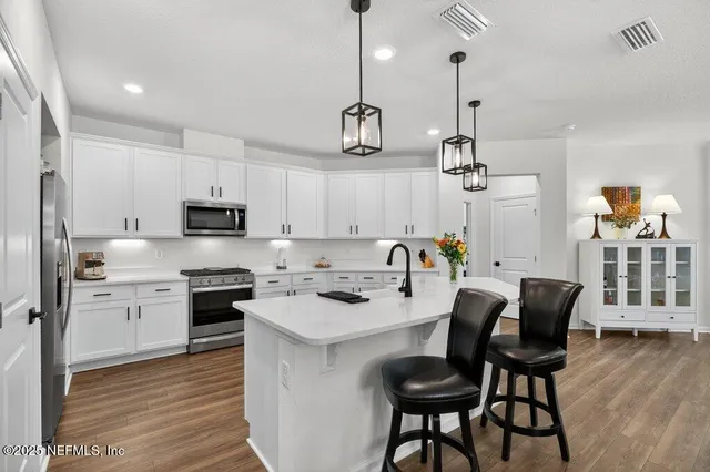 a kitchen with stainless steel appliances granite countertop a stove a sink and a microwave