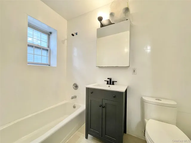 a bathroom with a toilet sink vanity tub and mirror