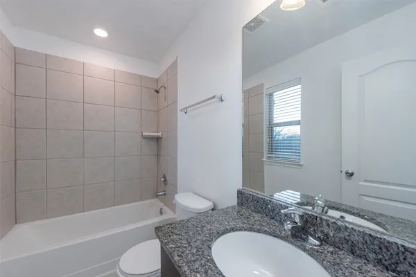 a bathroom with a granite countertop sink toilet a mirror and shower