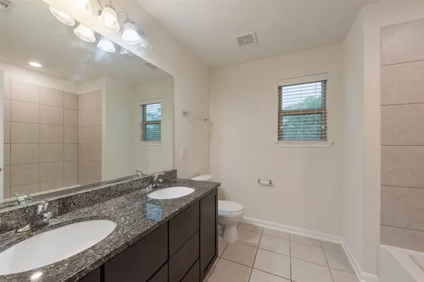 a bathroom with a granite countertop sink a toilet a mirror and a shower