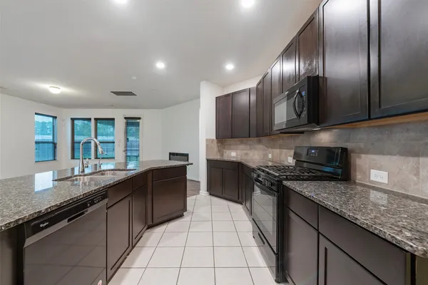 a large kitchen with granite countertop lots of counter space and a sink