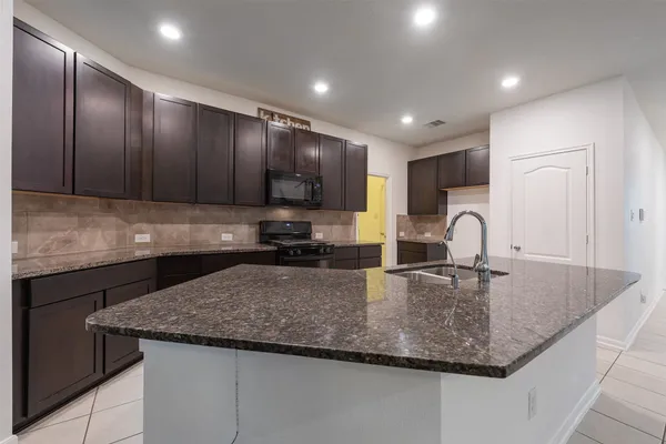 a kitchen with kitchen island granite countertop wooden cabinets a sink and stainless steel appliances