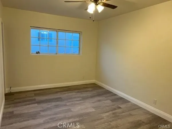 an empty room with wooden floor closet and chandelier fan