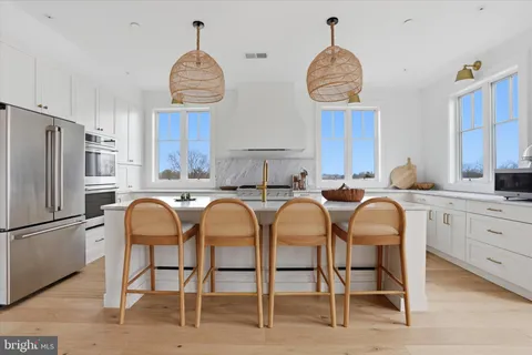 a very nice looking open kitchen with granite countertop a table chairs a refrigerator and cabinets