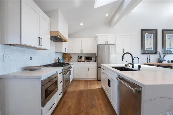 a kitchen with stainless steel appliances kitchen island wooden floors and white cabinets