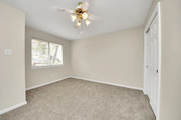 an empty room with windows and chandelier fan