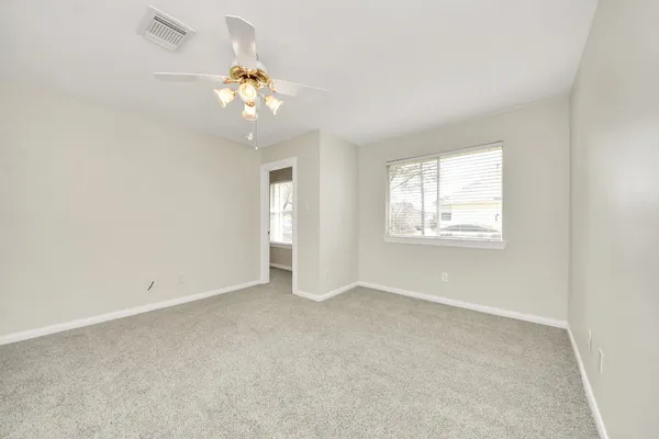 an empty room with windows and chandelier fan
