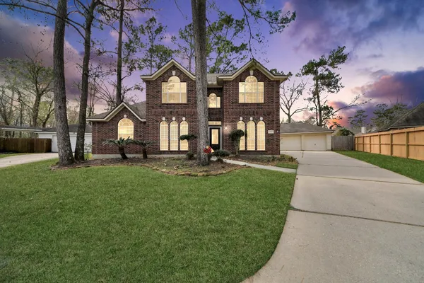 a view of a big house with a big yard and large trees