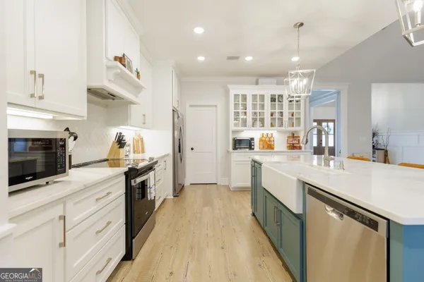 a kitchen with a stove a refrigerator and a dining table with wooden floor