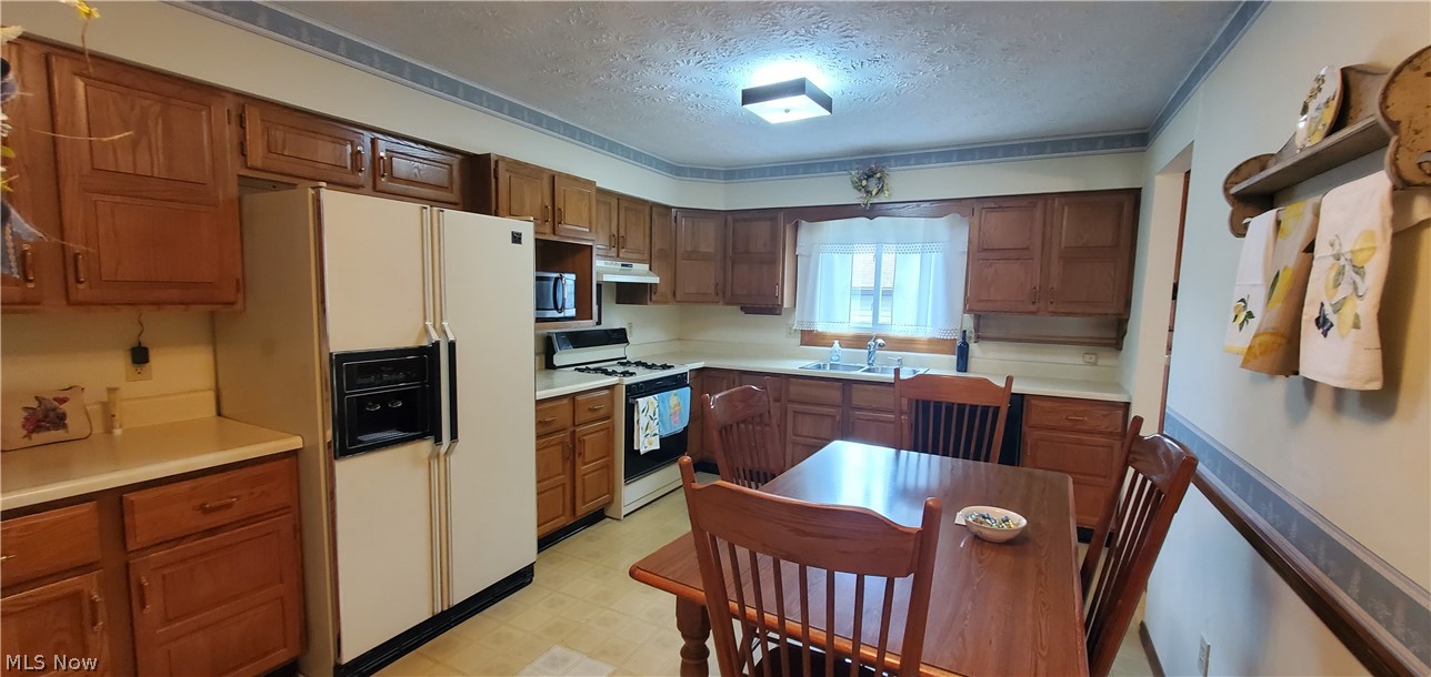 1515 East Bogart Road Sandusky, OH 44870 - Photo 7 of 23 Kitchen featuring sink, white appliances, light tile patterned floors, and a textured ceiling