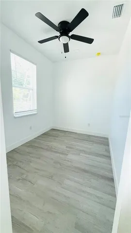 an empty room with a ceiling fan and window