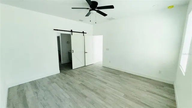 a view of empty room with wooden floor and ceiling fan