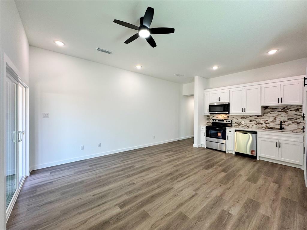 1811 Washington Street Commerce, TX 75428 - Photo 11 of 36 a view of kitchen with stainless steel appliances wooden floors white refrigerator a microwave oven a stove with white cabinets