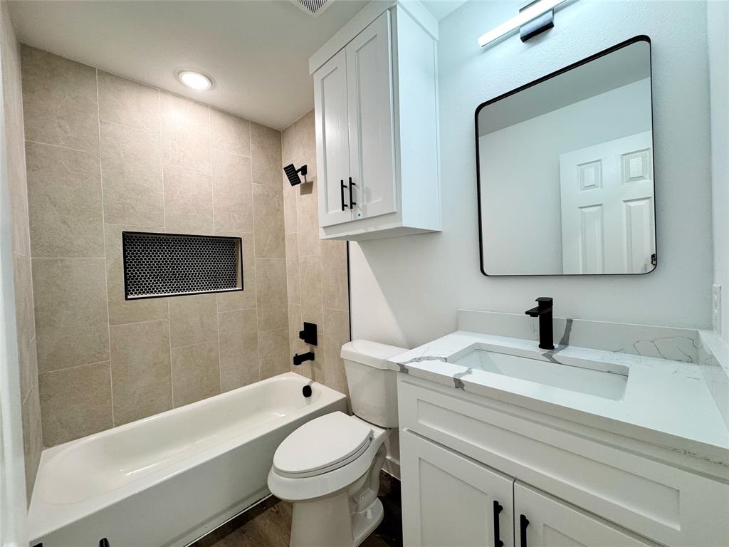 1811 Washington Street Commerce, TX 75428 - Photo 15 of 36 a bathroom with a sink a toilet and a mirror