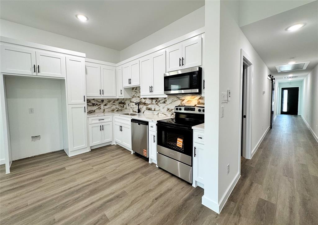 1811 Washington Street Commerce, TX 75428 - Photo 17 of 36 a kitchen with stainless steel appliances granite countertop a stove top oven a sink dishwasher and a refrigerator