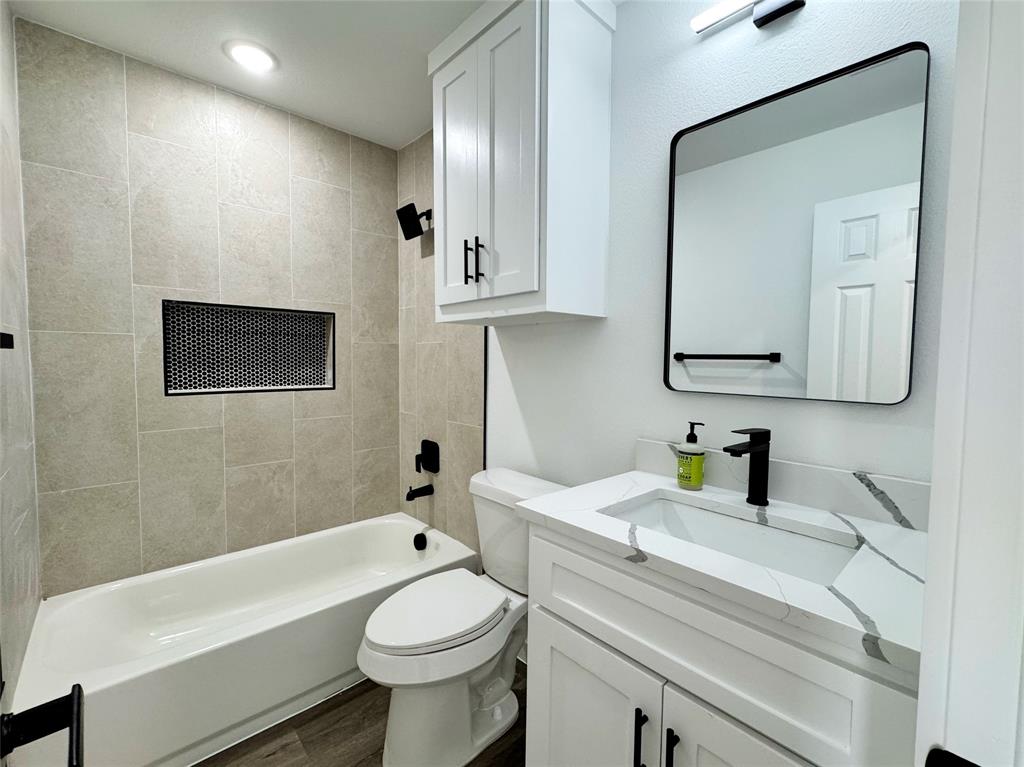 1811 Washington Street Commerce, TX 75428 - Photo 18 of 36 a bathroom with a toilet a sink a mirror and bathtub