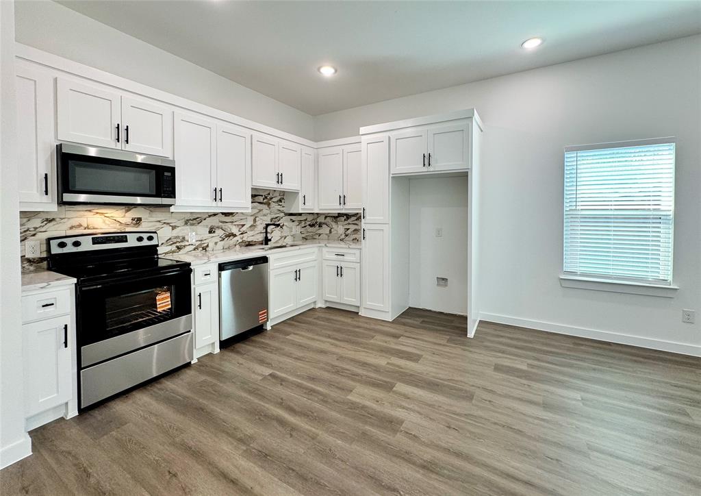 1811 Washington Street Commerce, TX 75428 - Photo 22 of 36 a kitchen with stainless steel appliances a stove top oven a sink dishwasher and a refrigerator