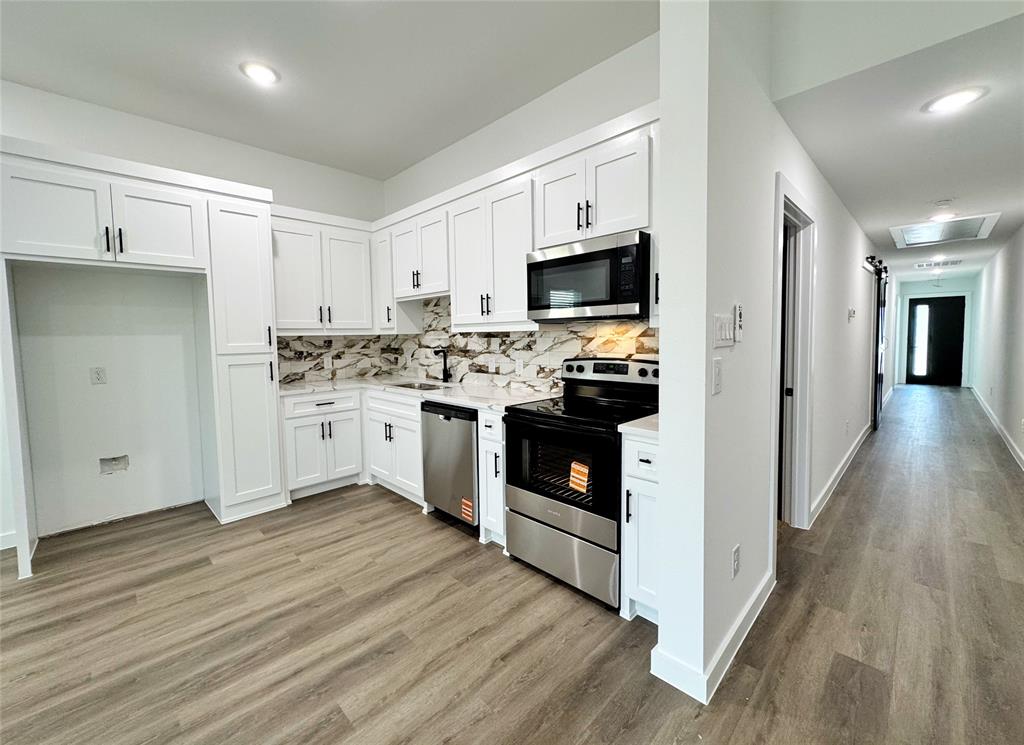 1811 Washington Street Commerce, TX 75428 - Photo 27 of 36 a kitchen with stainless steel appliances a white stove top oven and refrigerator