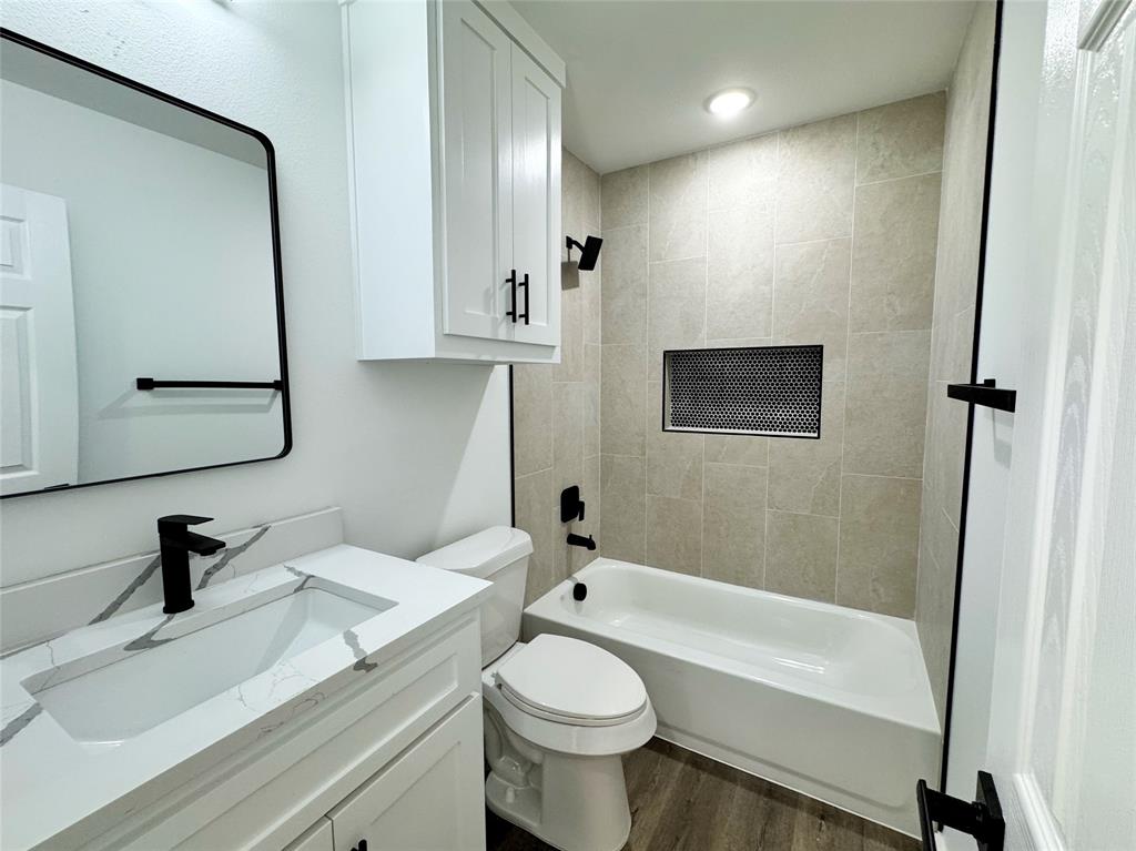 1811 Washington Street Commerce, TX 75428 - Photo 10 of 36 a bathroom with a sink a toilet and a mirror