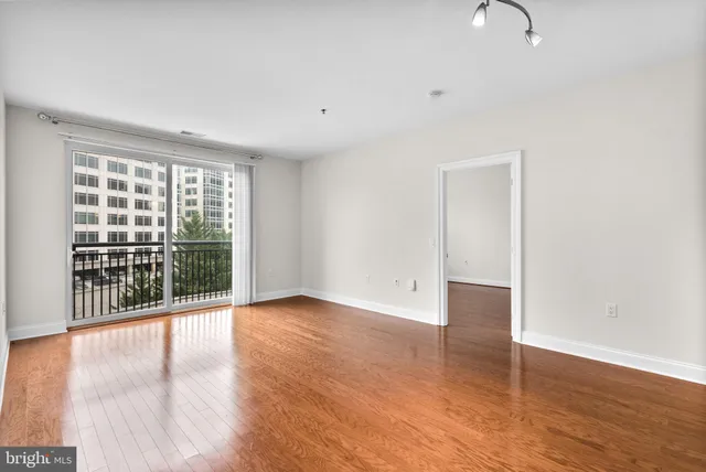 a view of an empty room with wooden floor and a window