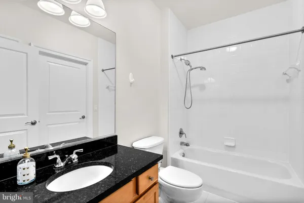 a bathroom with a granite countertop sink toilet a mirror and shower