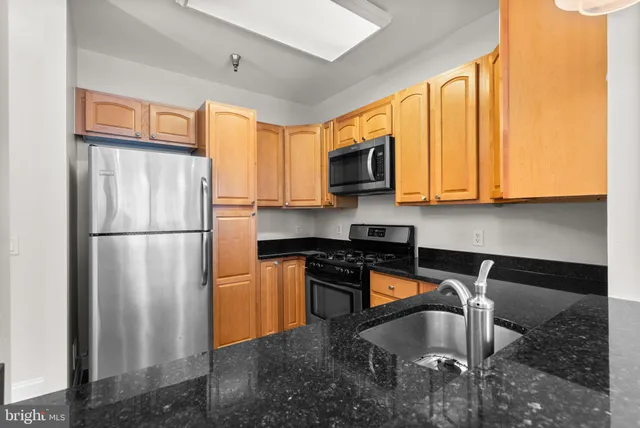 a kitchen with stainless steel appliances granite countertop a refrigerator a stove a sink and a microwave