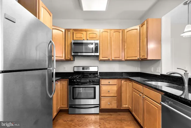 a kitchen with stainless steel appliances granite countertop a stove a sink and a microwave