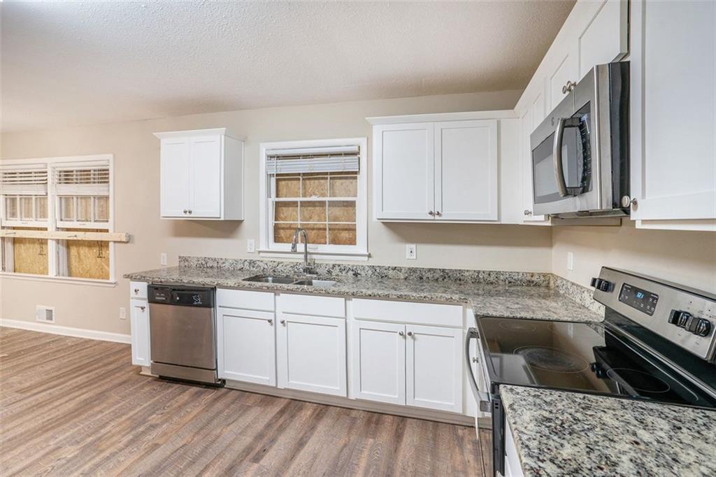 1714 Camperdown Circle Decatur, GA 30035 - Photo 13 of 15 a kitchen with stainless steel appliances granite countertop a stove top oven a sink dishwasher and white cabinets with wooden floor