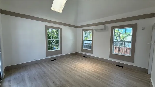 a view of an empty room with wooden floor and a window