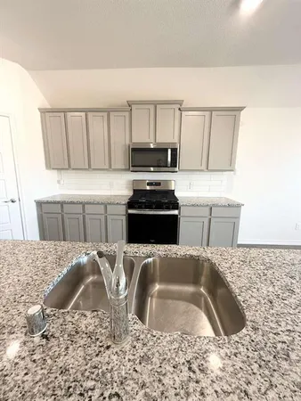 a kitchen with granite countertop a sink and a stove top oven