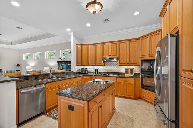 a kitchen with stainless steel appliances granite countertop a sink a stove and a refrigerator