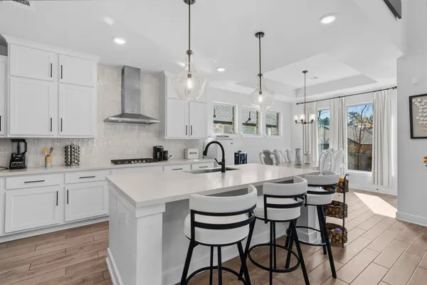 a kitchen with stainless steel appliances granite countertop a sink a stove a refrigerator and island with wooden floor