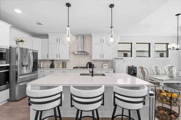 a kitchen with stainless steel appliances kitchen island a dining table chairs and a view of living room