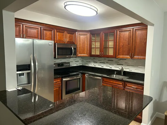a kitchen with granite countertop stainless steel appliances and wooden cabinets