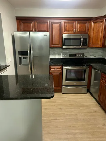 a kitchen with granite countertop a refrigerator and a stove top oven