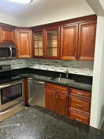 a kitchen with granite countertop wooden cabinets stainless steel appliances and a window