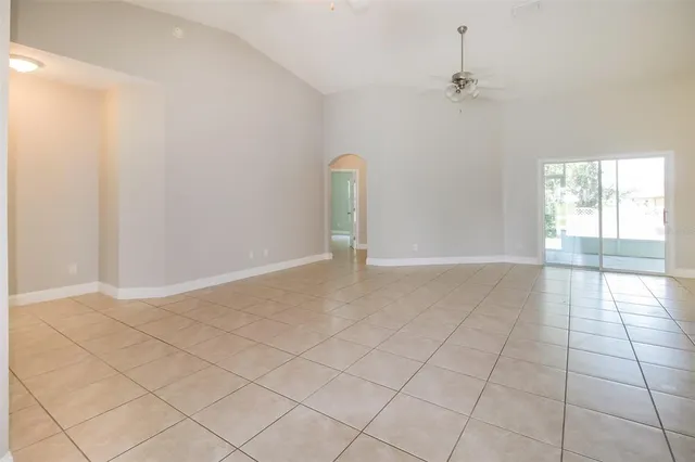 an empty room with kitchen and chandelier fan