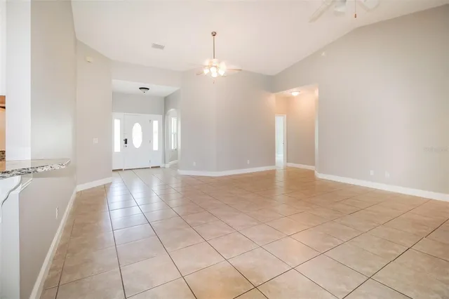 an empty room with chandelier fan and windows