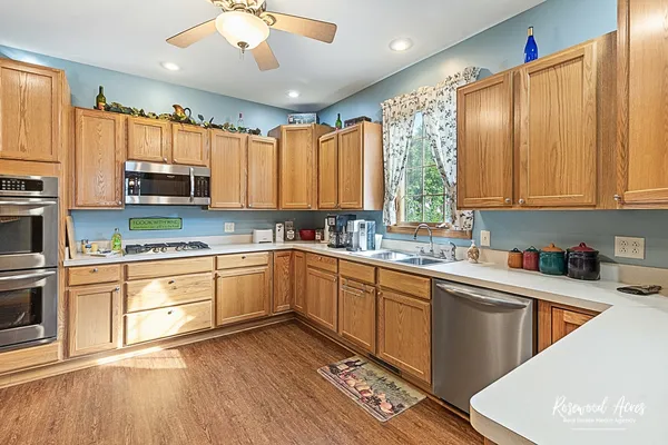a kitchen with stainless steel appliances granite countertop a stove a sink dishwasher and a microwave oven with cabinets