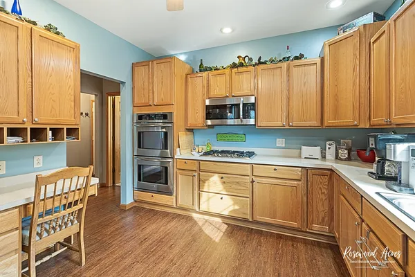 a kitchen with stainless steel appliances a microwave a stove a sink dishwasher a refrigerator with a dining table and chairs with wooden floor