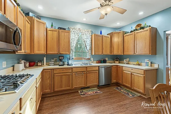 a kitchen with stainless steel appliances granite countertop a stove top oven a sink dishwasher and cabinets with wooden floor