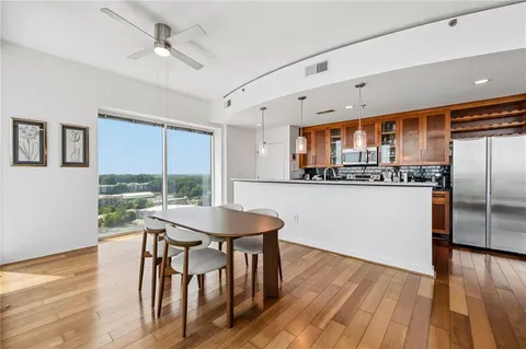 a kitchen with stainless steel appliances a table chairs refrigerator and wooden floor