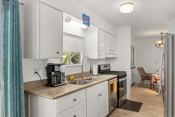 a kitchen with stainless steel appliances granite countertop a stove a sink and a white cabinets