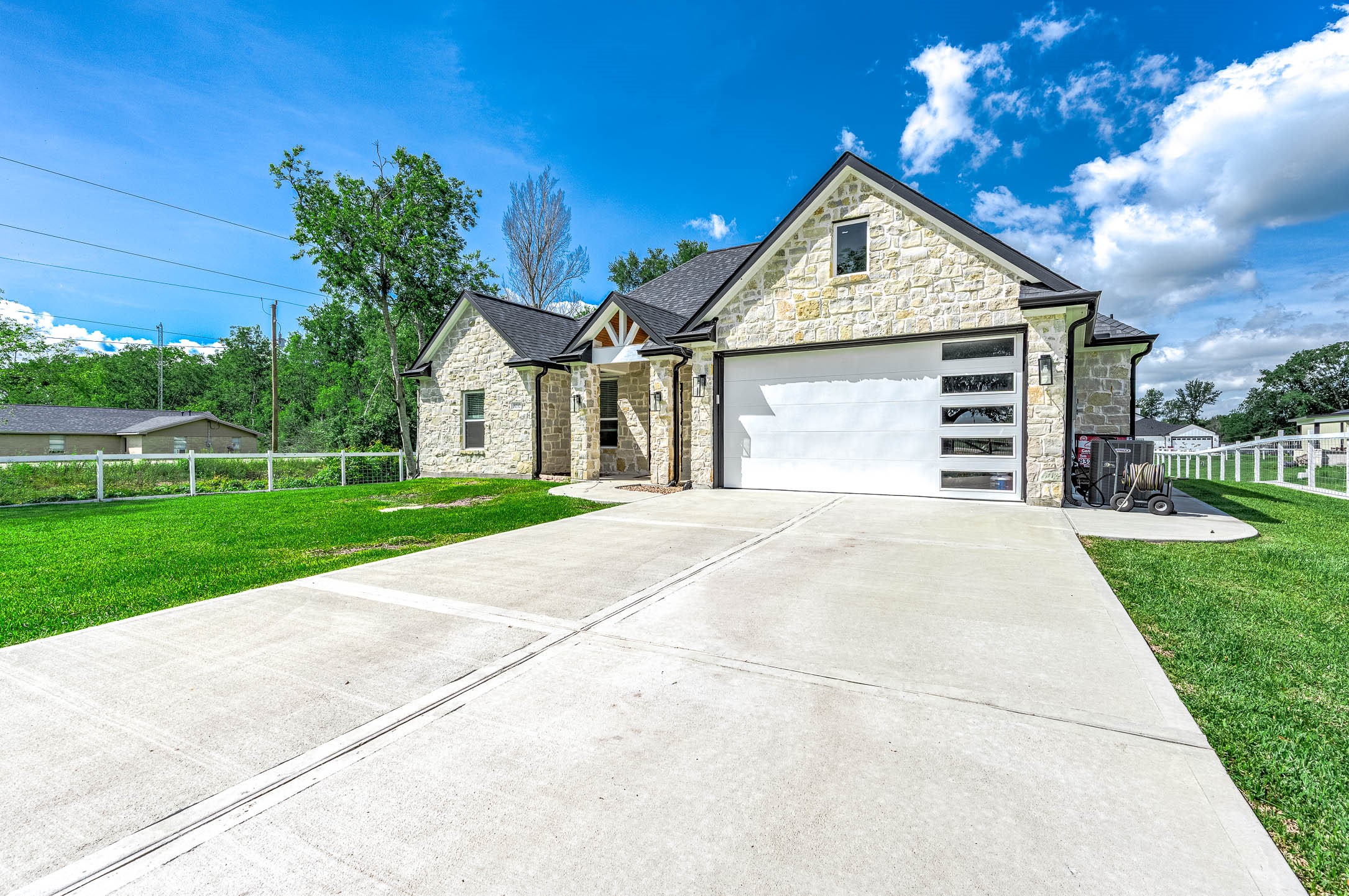 8032 Short Road Needville, TX 77461 - Photo 48 of 50 This view highlights the home’s attractive stone exterior, spacious driveway, and attached two-car garage. The well-maintained landscaping and peaceful surroundings add to the property’s overall curb appeal and welcoming atmosphere.