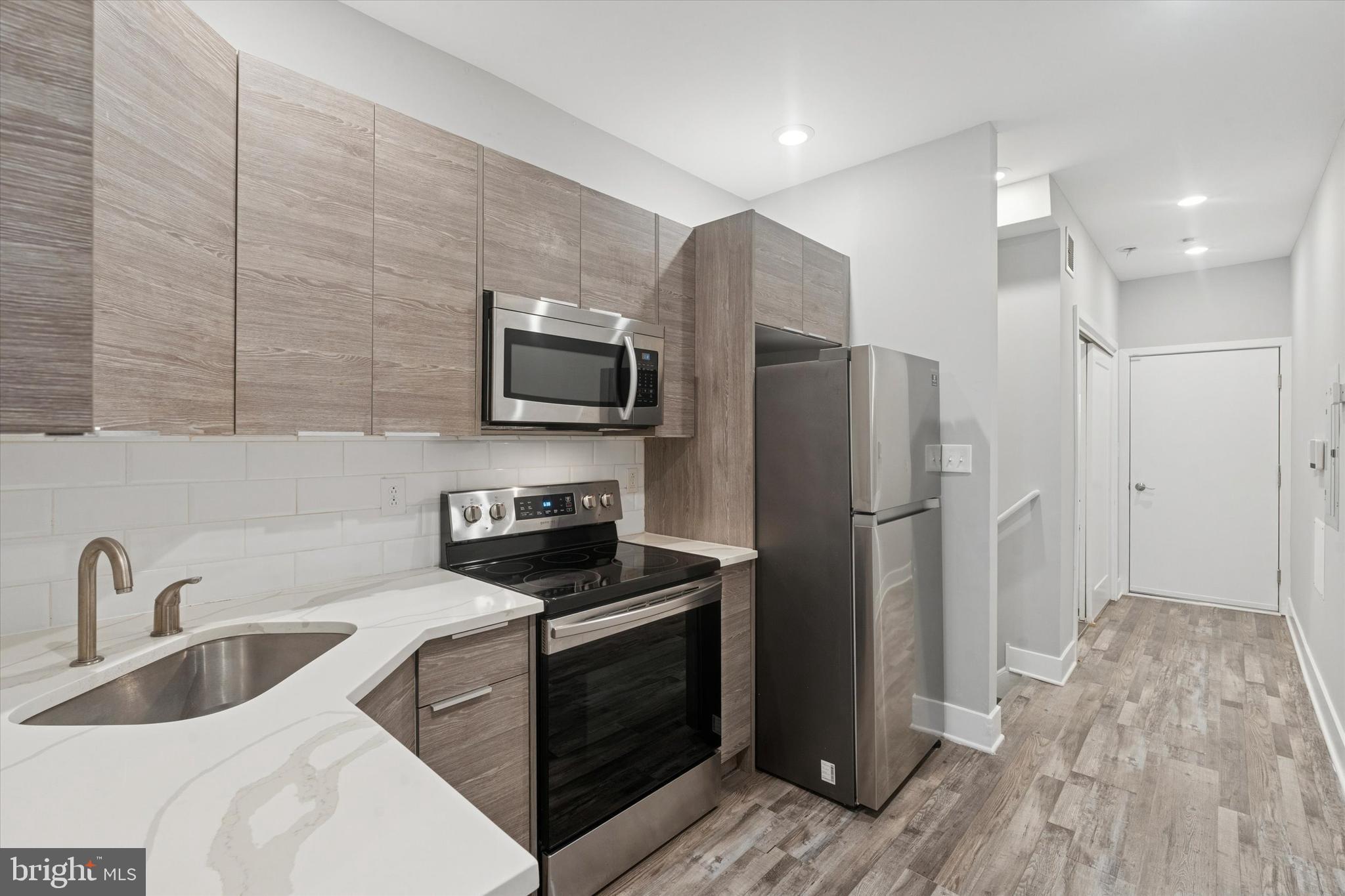 3817 Wallace Street Philadelphia, PA 19104 - Photo 2 of 25 a kitchen that has a refrigerator a sink and white cabinets with wooden floor