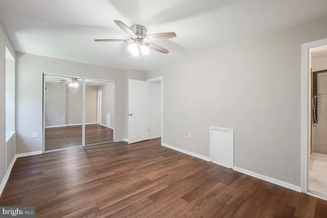 an empty room with wooden floor and fan