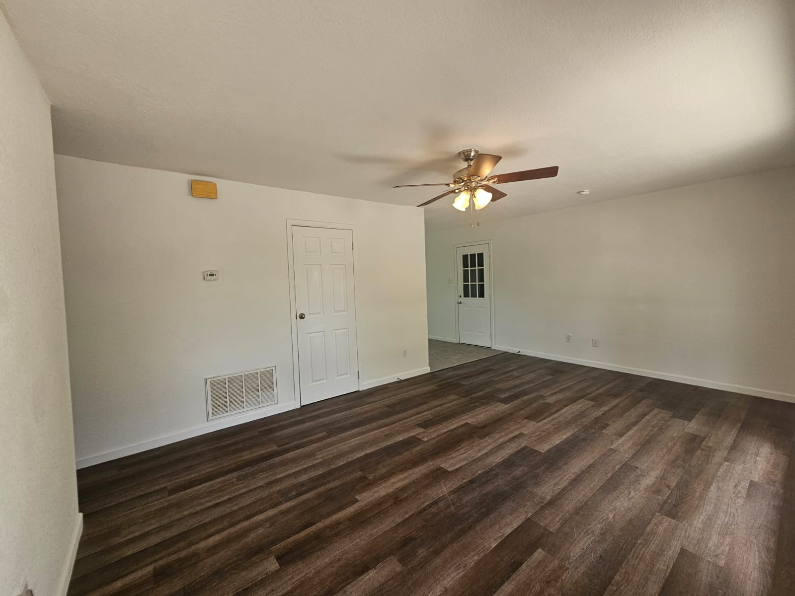 1401 Trinity Street Lockhart, TX 78644 - Photo 4 of 31 Spacious room featuring wood-finish flooring, white walls, and a ceiling fan