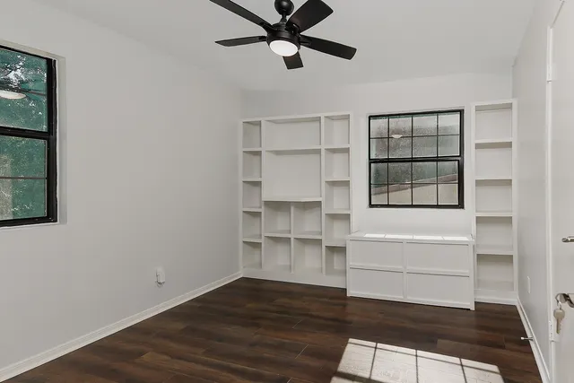 a view of an empty room with a window and wooden floor